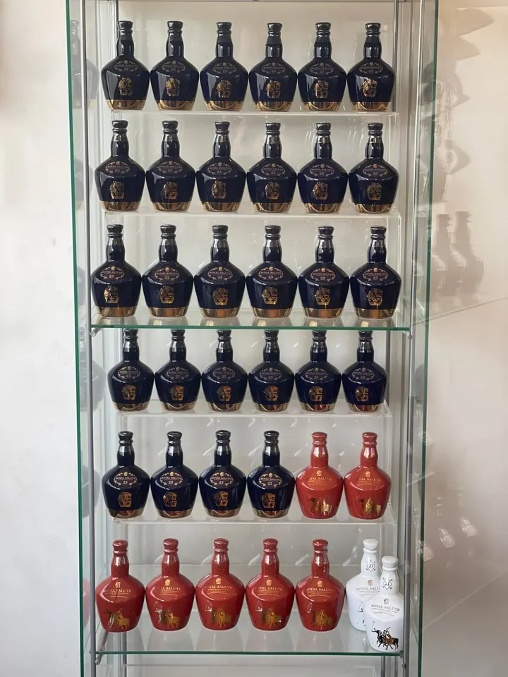 Glass cabinet with rows of navy Royal Salute 25 Year Old miniatures and red Polo Estancia miniatures